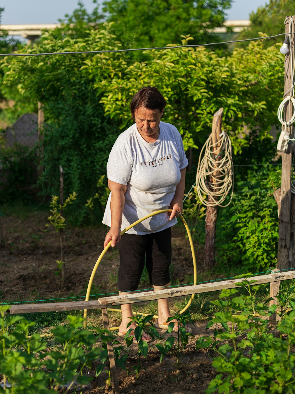 Una mujer usando una manguera de jardín en un jardín