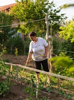 a woman in white shirt holding a garden hose