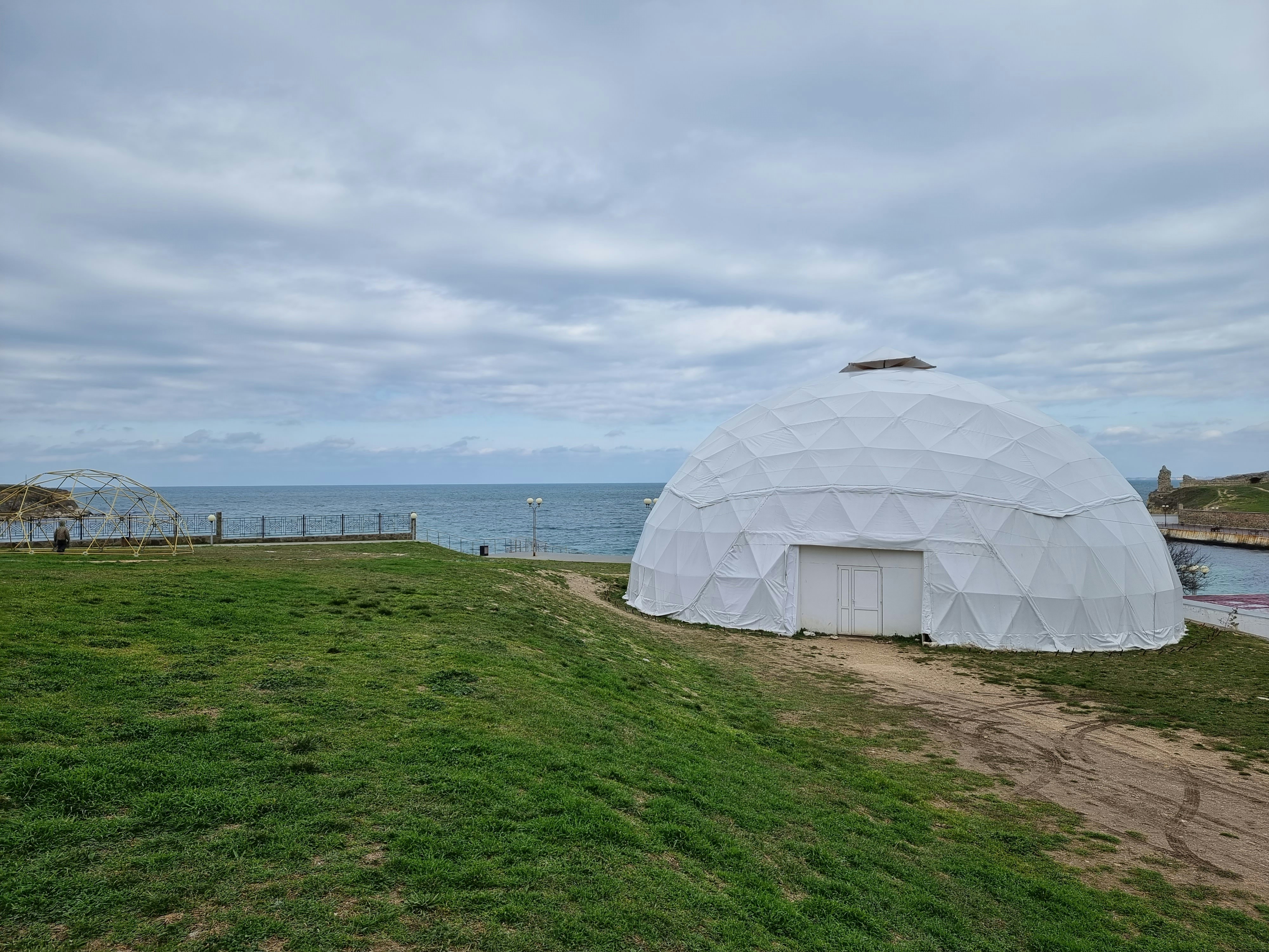 una grande cupola bianca seduta in cima a un campo verde lussureggiante