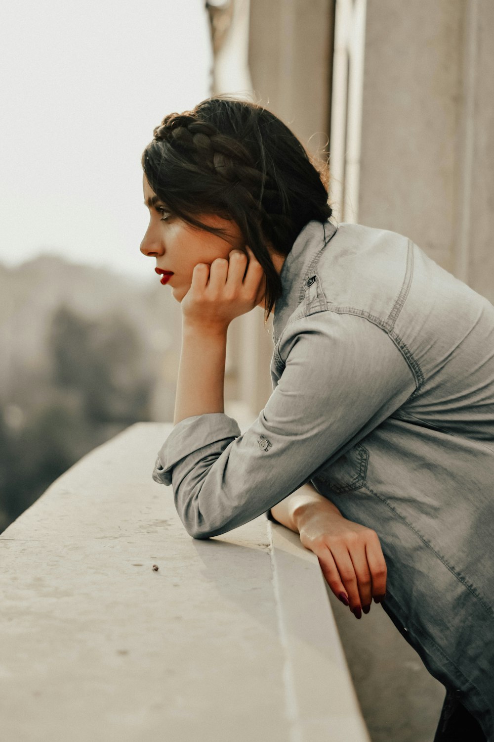 a woman leaning on a ledge talking on a cell phone