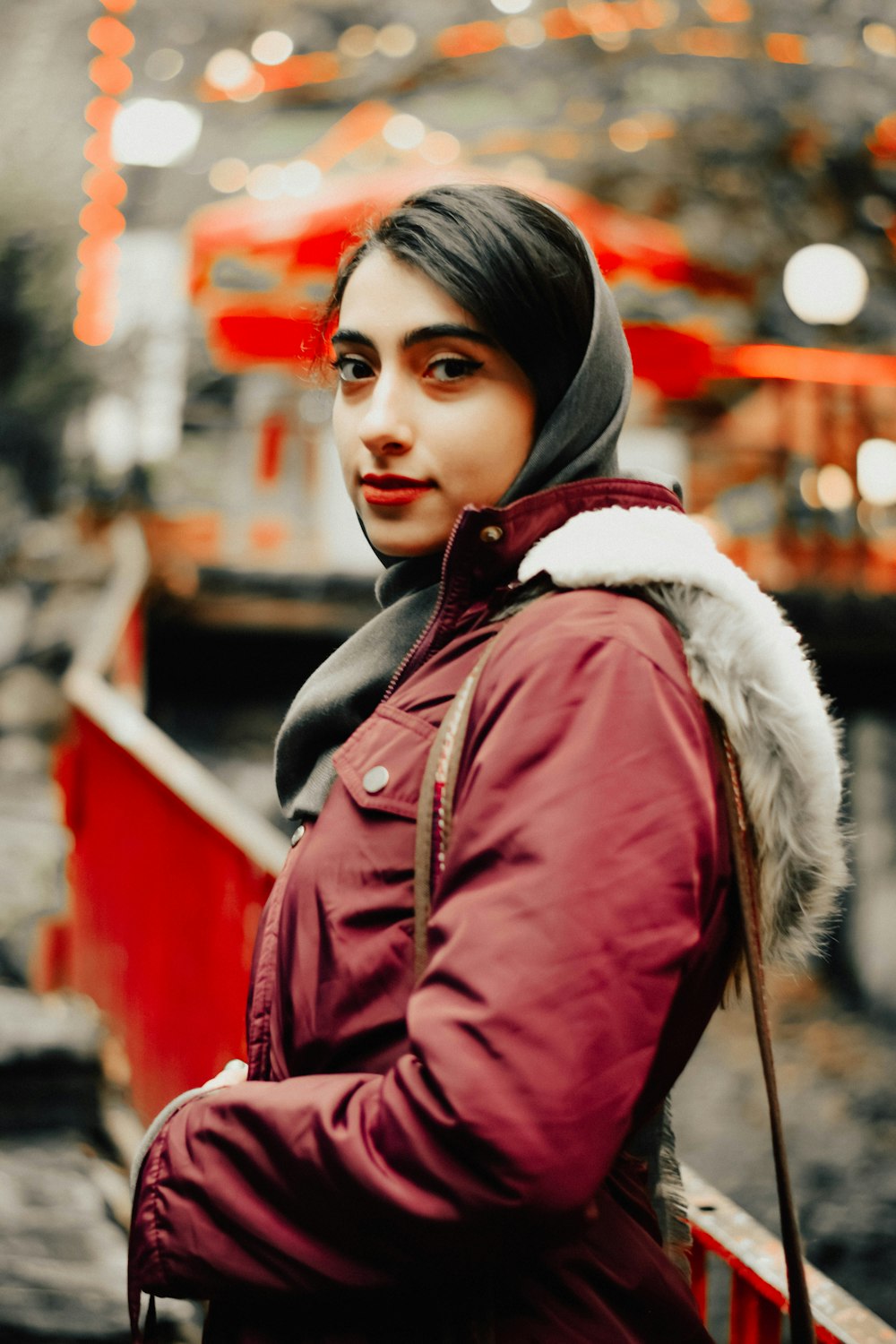 a woman in a red jacket is standing on a bridge