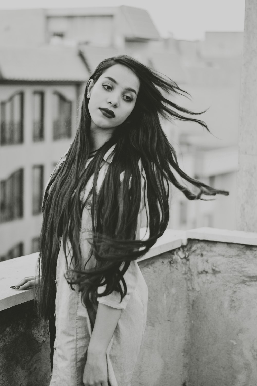 a woman with long hair standing on a balcony