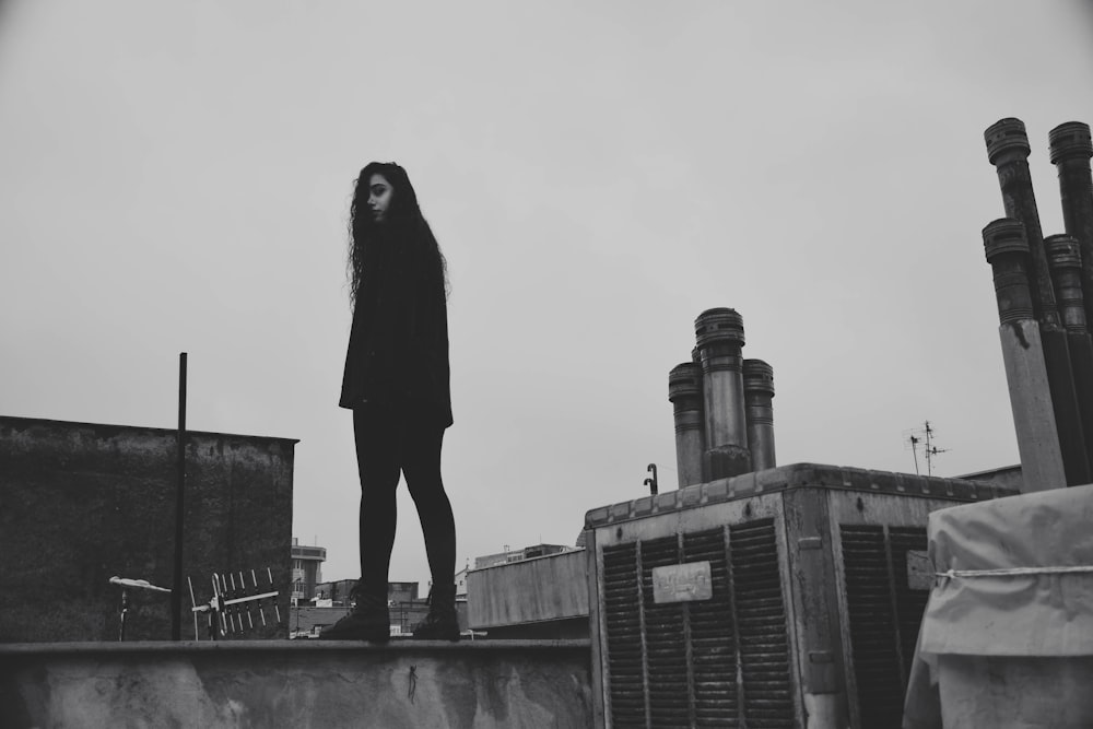 a woman standing on top of a roof next to a building