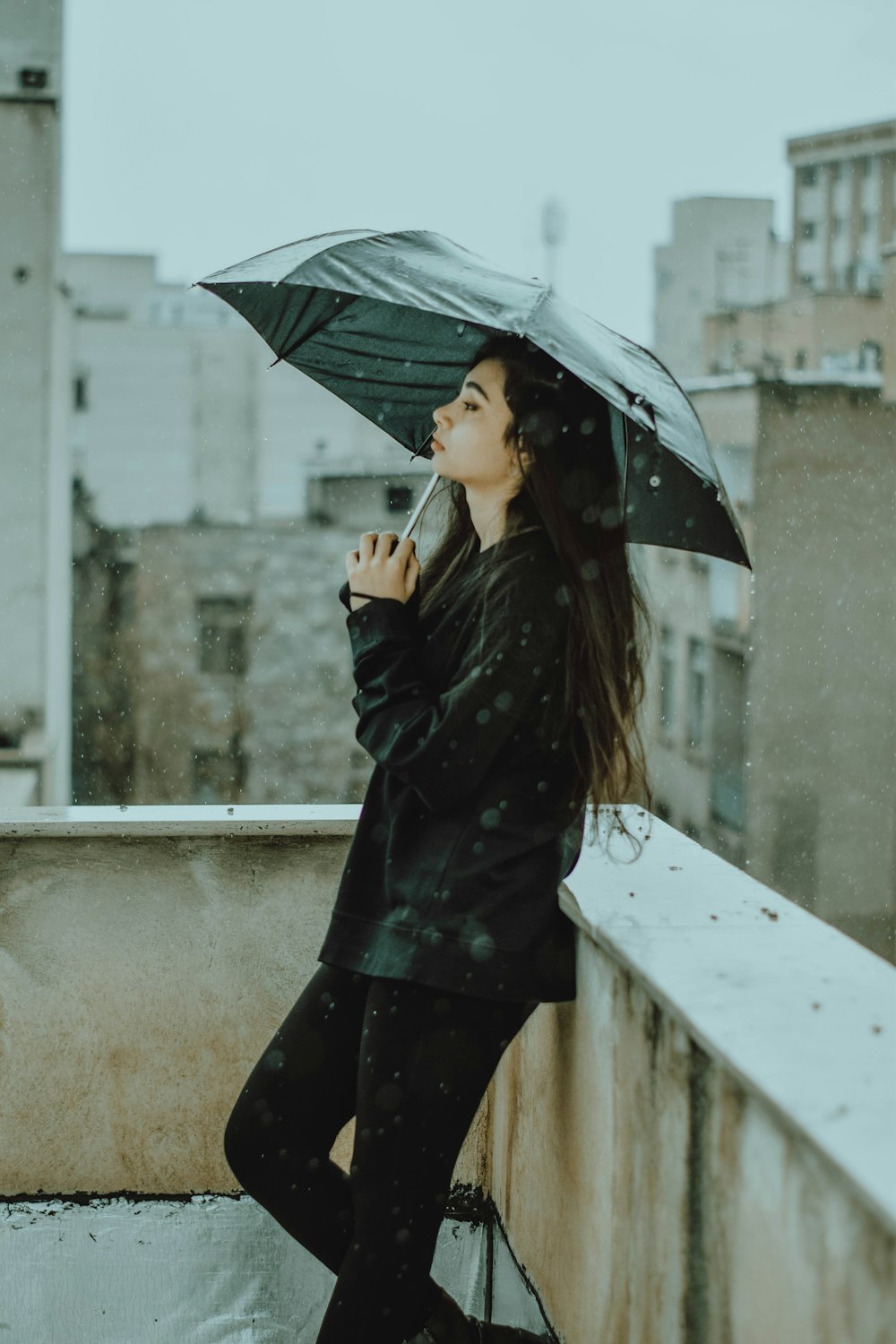 a woman standing on a balcony holding an umbrella