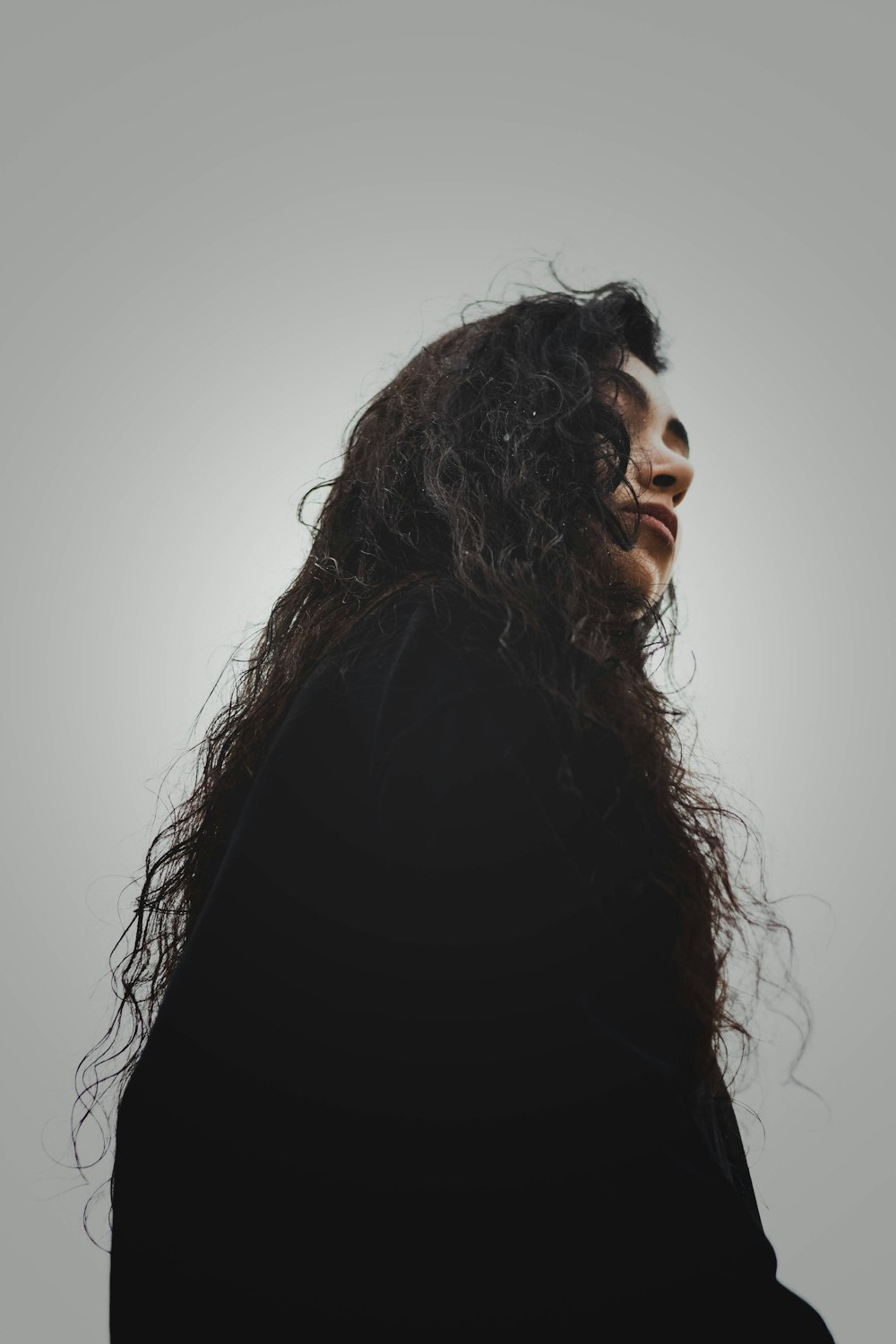 a woman with long hair standing in front of a gray background