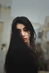 a woman with long hair standing in front of a building