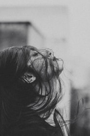 a black and white photo of a woman with her hair blowing in the wind