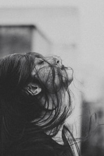 a black and white photo of a woman with her hair blowing in the wind