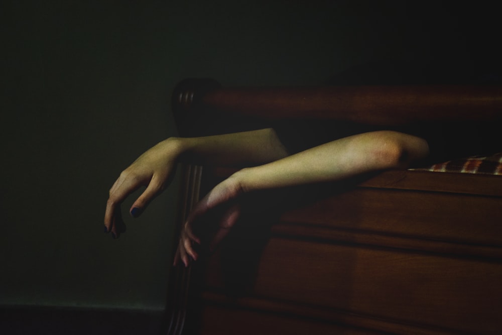 a woman's hands resting on a bed in a dark room