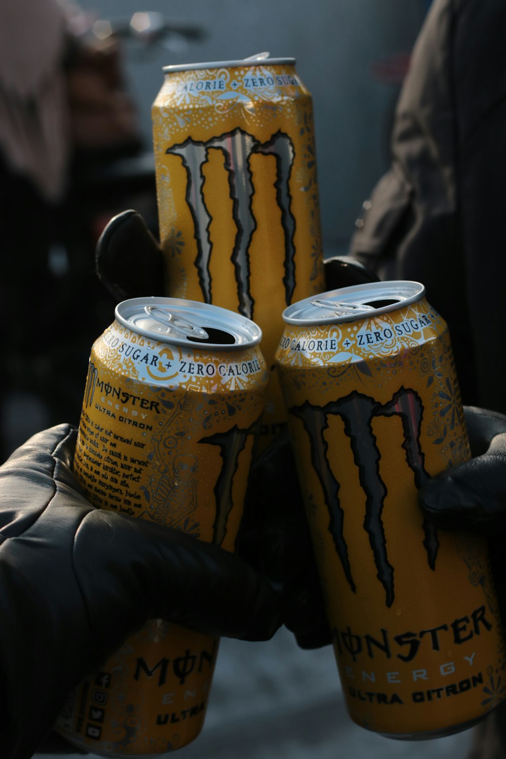 a person holding four cans of monster energy drink