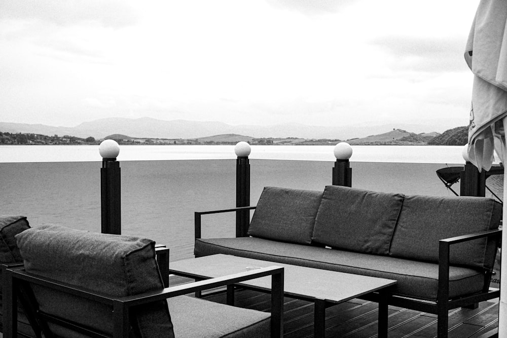 a black and white photo of a couch and chairs on a deck