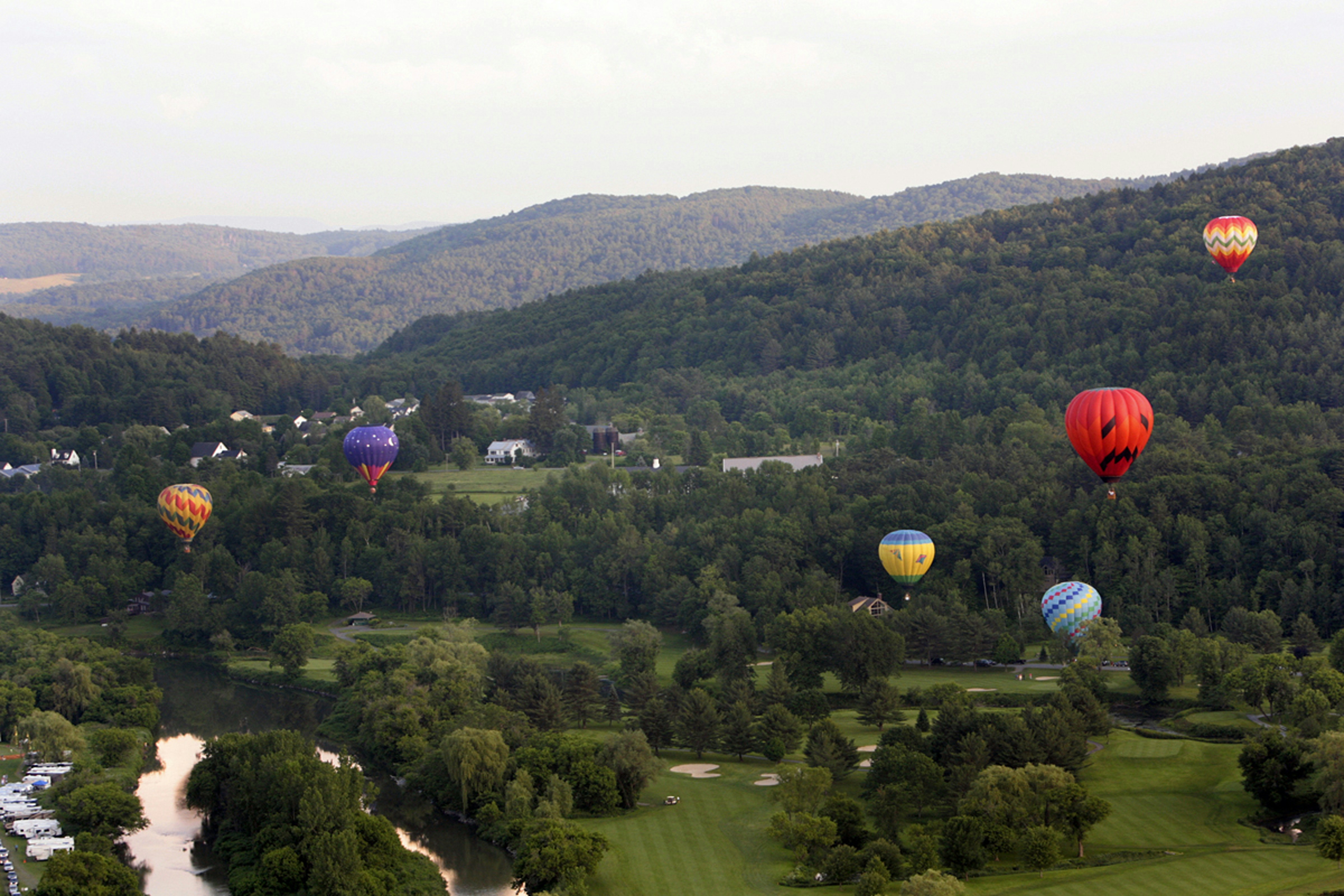 a group of hot air balloons flying over a golf course