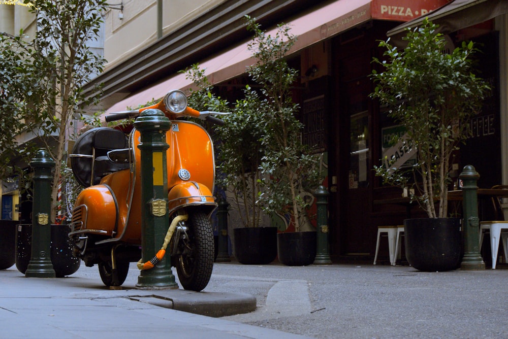 uma scooter laranja estacionada ao lado de uma rua