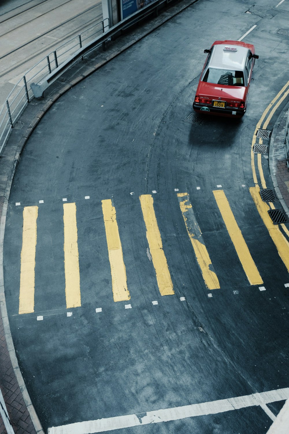 a red car driving down a street next to a traffic light