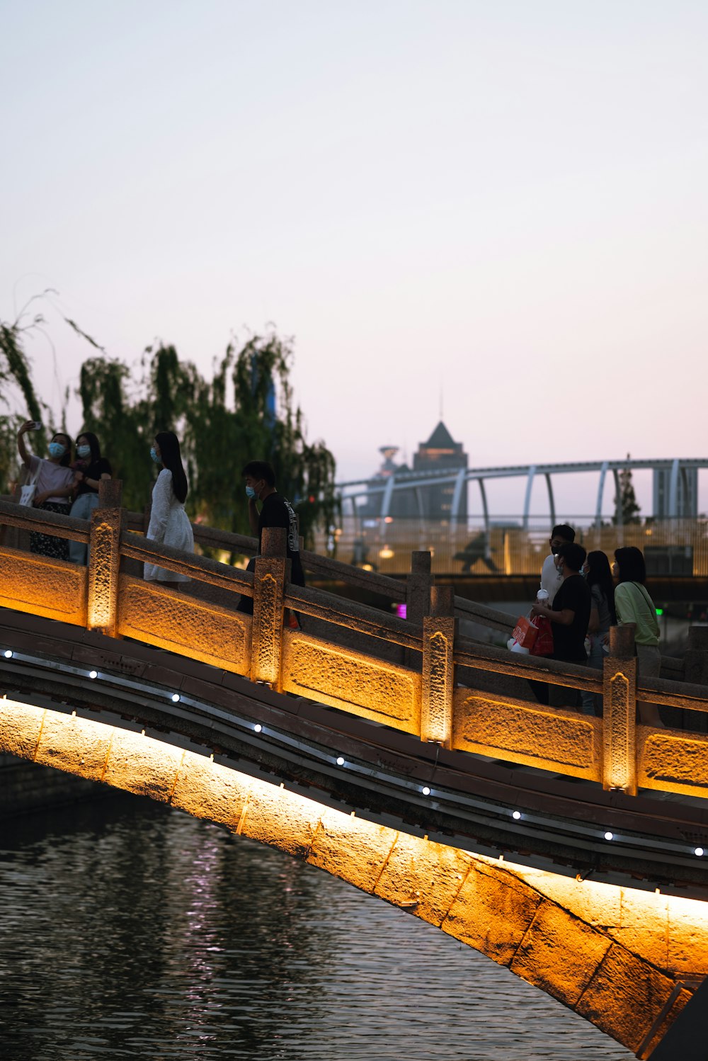 a group of people walking across a bridge over water