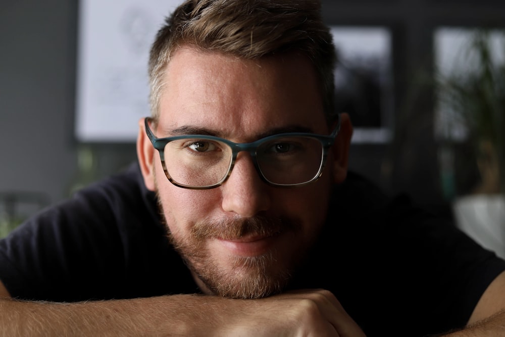 a man with glasses leaning on a table