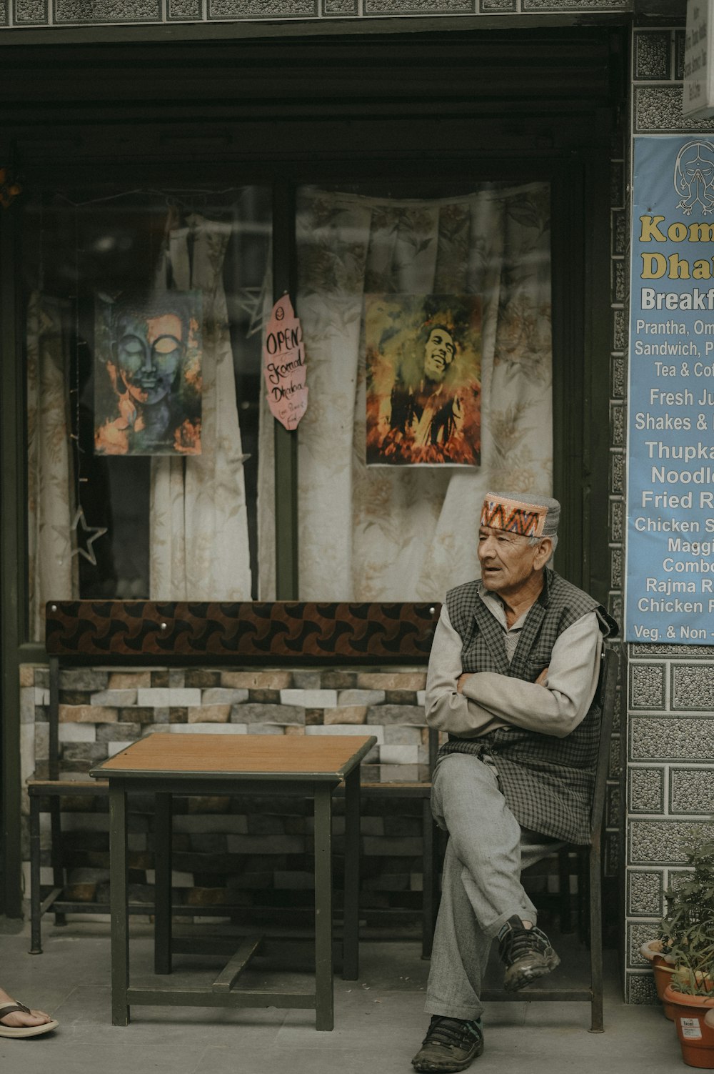 a man sitting on a bench in front of a restaurant