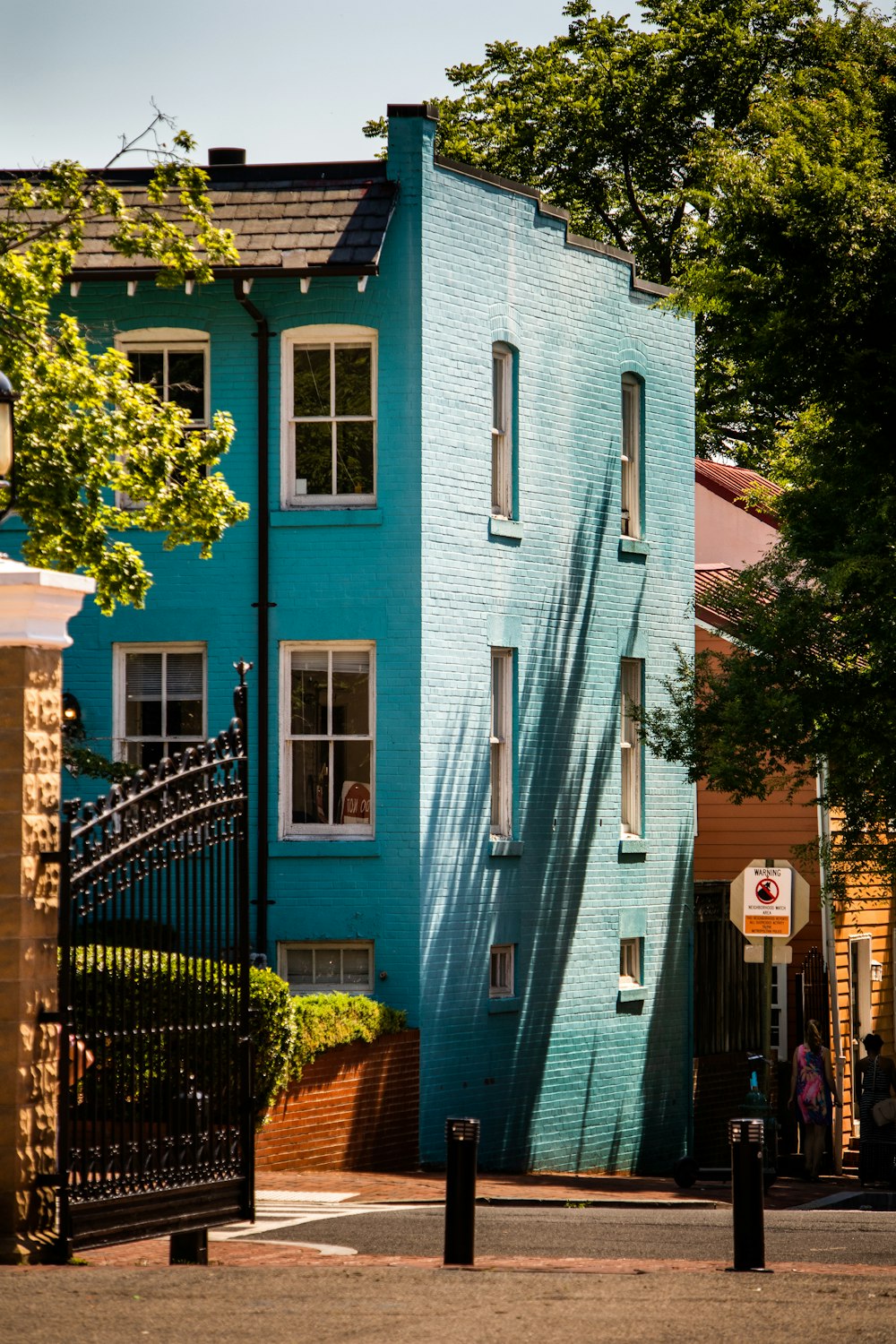 um edifício azul alto sentado ao lado de uma árvore verde exuberante