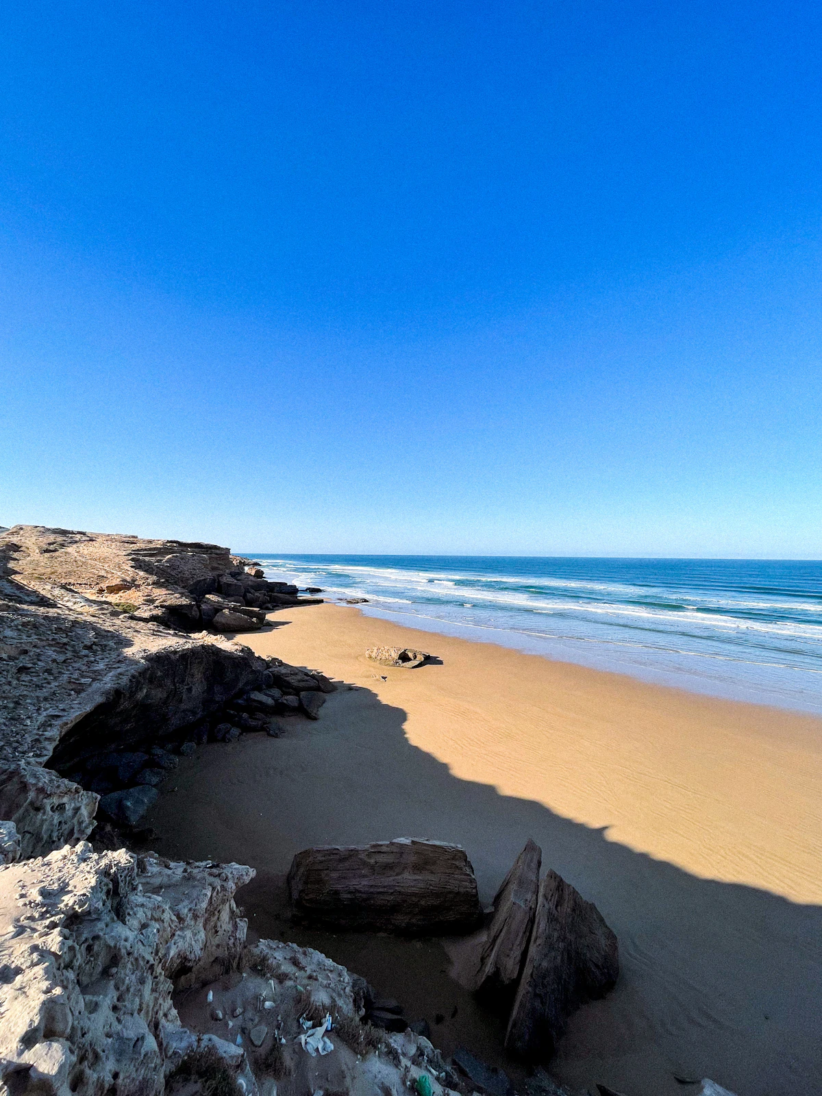 A sandy beach below low pale cliffs at Legzira, near Sidi Ifni