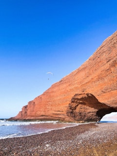 a person flying a kite on a rocky beach
