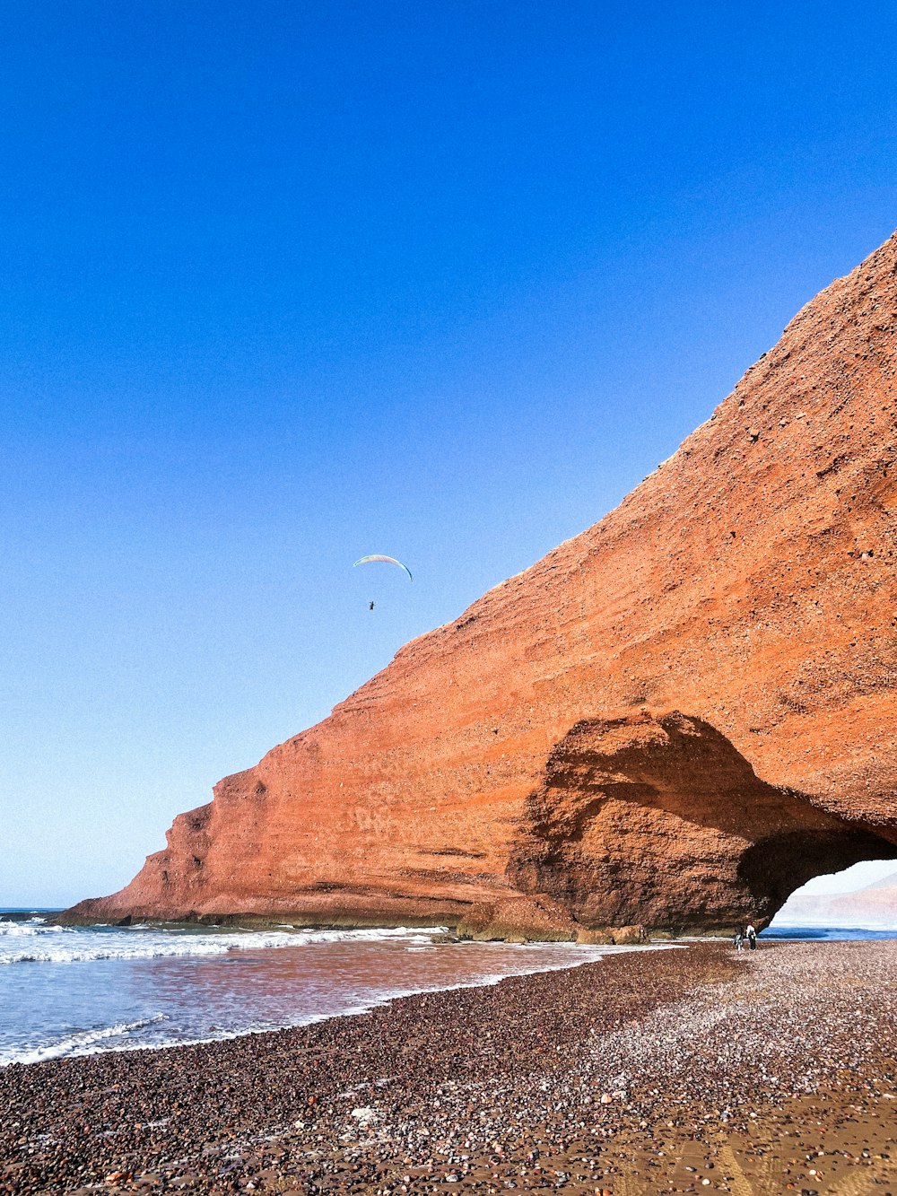 a person flying a kite on a rocky beach