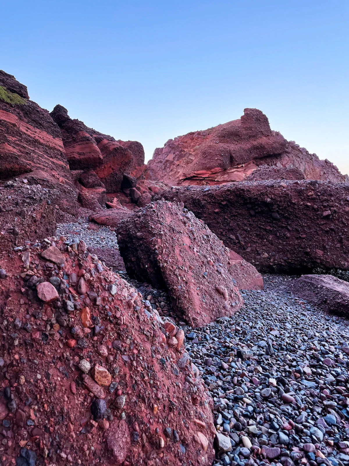 Red conglomerate boulders on a pebble beach at Legzira