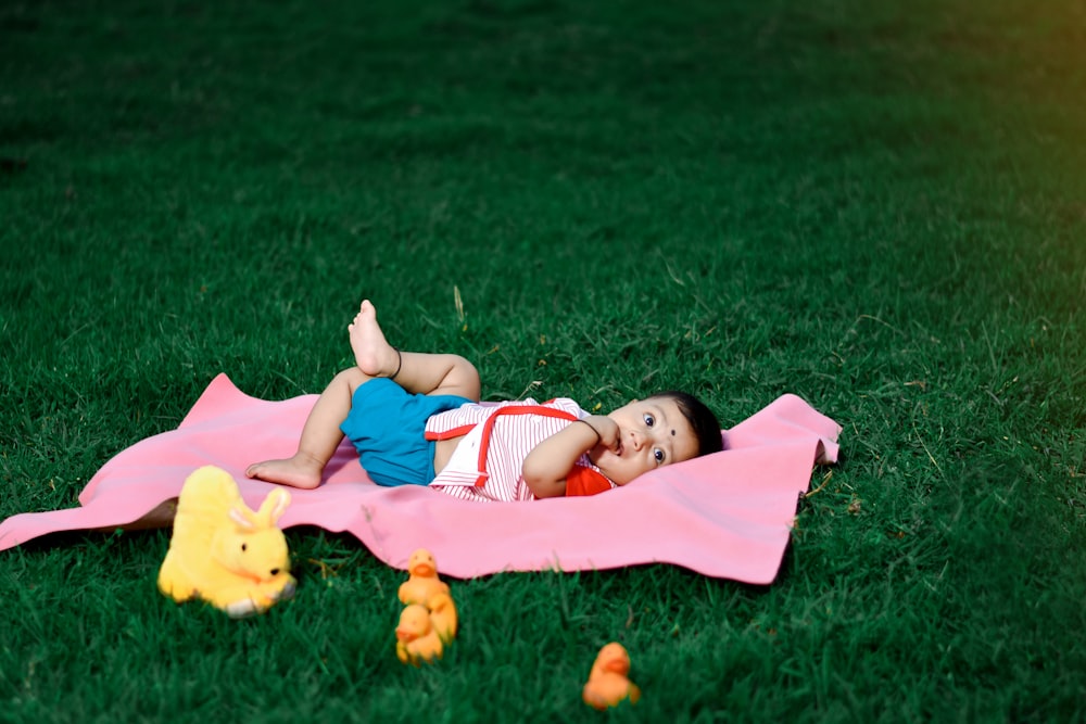 a little girl laying on a blanket in the grass