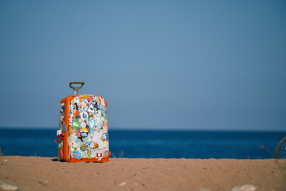 a piece of luggage sitting on top of a sandy beach