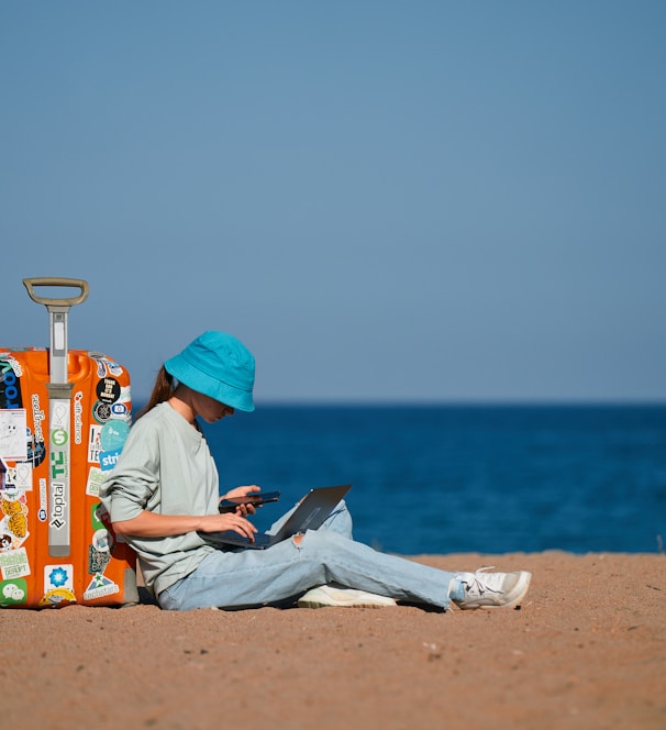 a person sitting on the beach with a suitcase