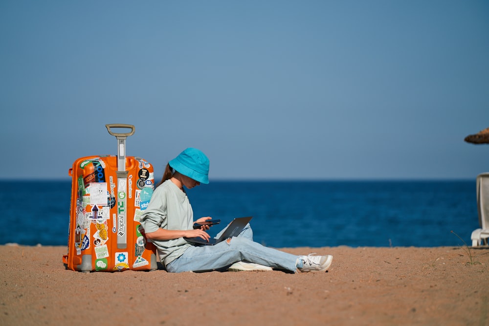 Eine Person, die mit einem Koffer am Strand sitzt