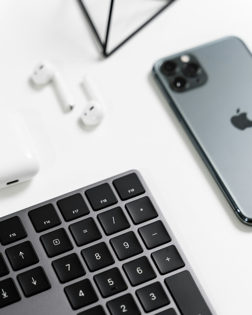 an iphone, ear buds, and a keyboard on a table