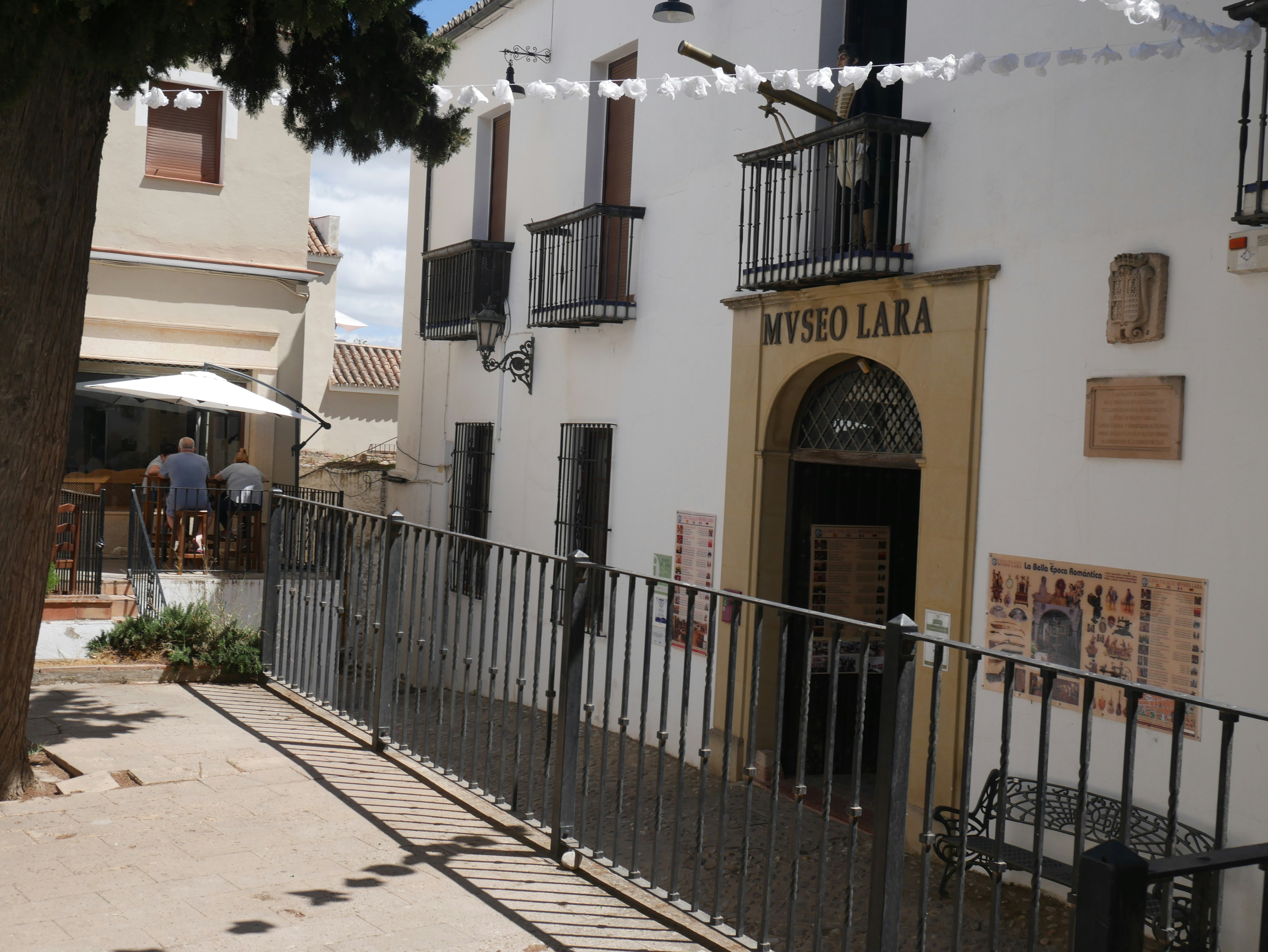 a white building with a black fence and a tree