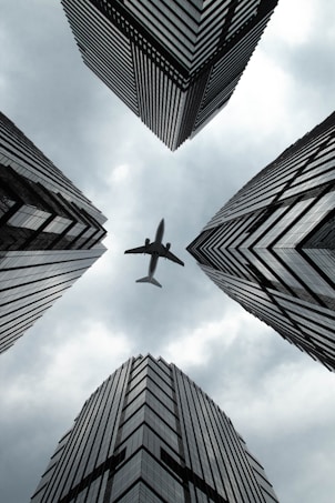 an airplane is flying through the sky between tall buildings