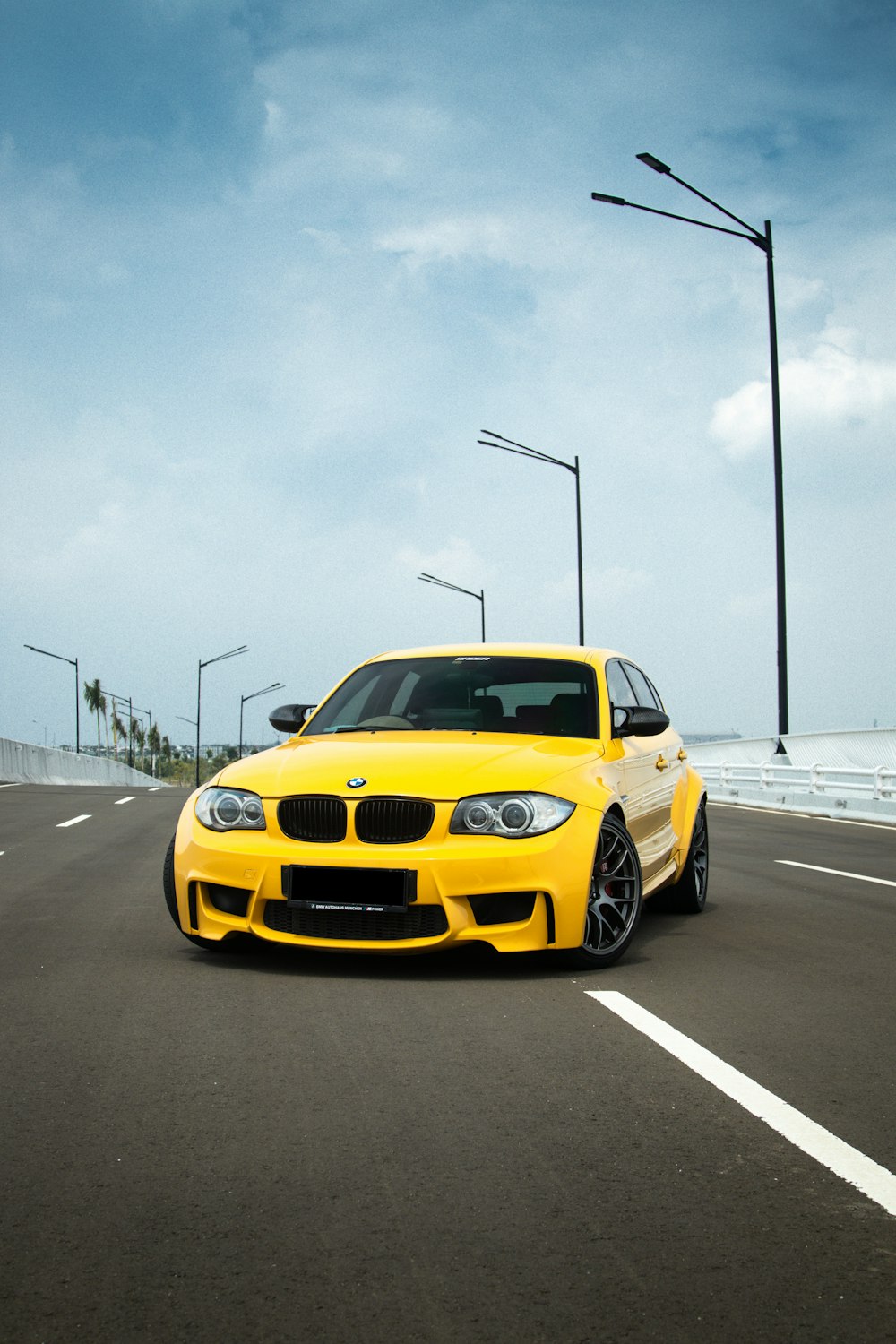 a yellow car driving down a road next to the ocean