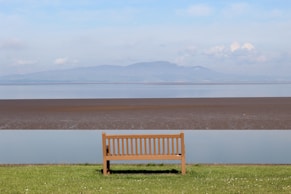 a wooden bench sitting on top of a lush green field