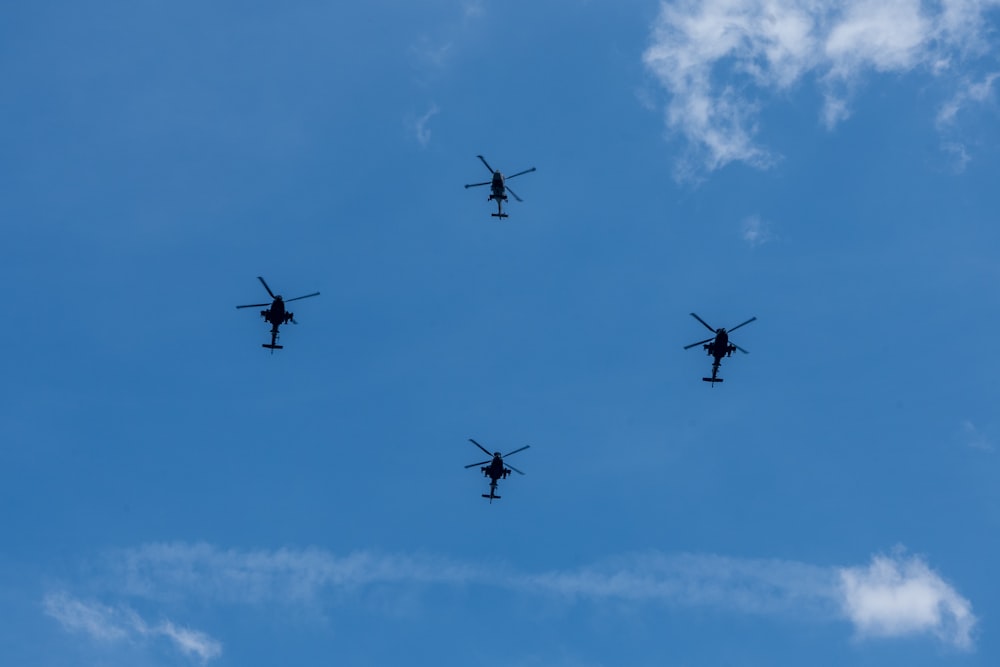 a group of four airplanes flying through a blue sky