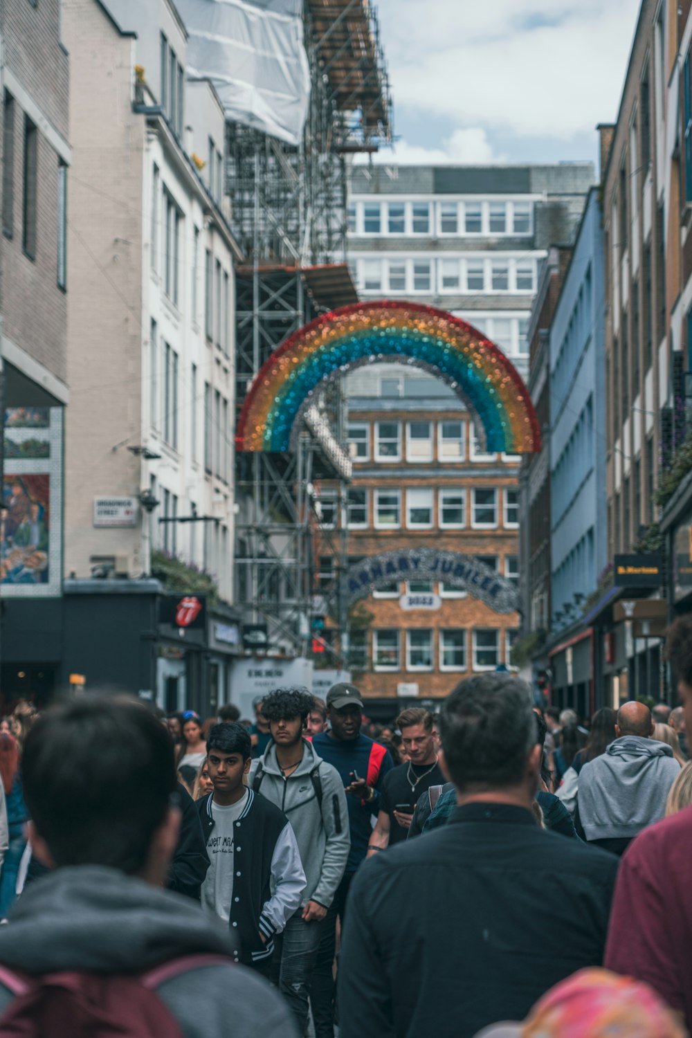 a crowd of people walking down a street next to tall buildings