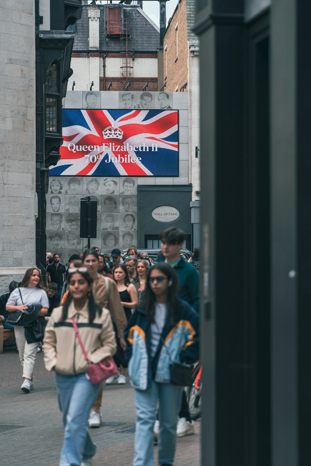 a group of people walking down a street next to tall buildings