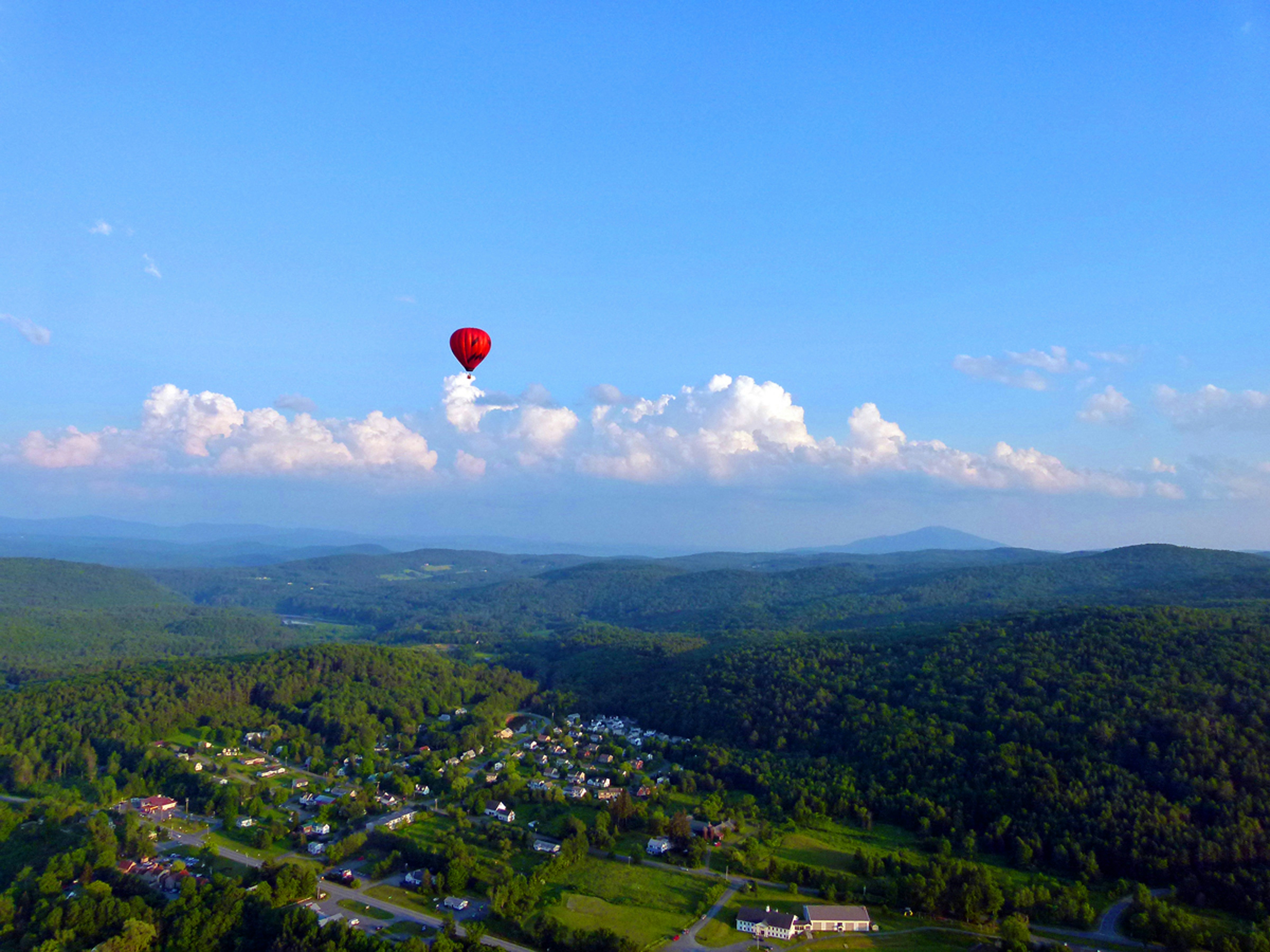 a hot air balloon flying over a lush green hillside