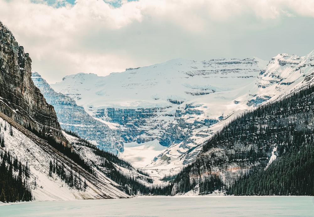 a snow covered mountain range with a lake in the foreground