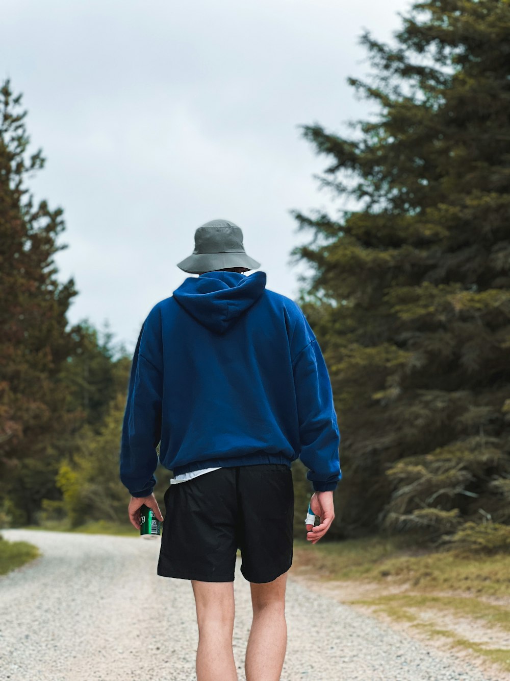 a man walking down a dirt road in the woods