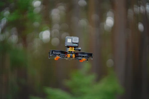 A compact drone hovering over a forest, ready to capture aerial footage.