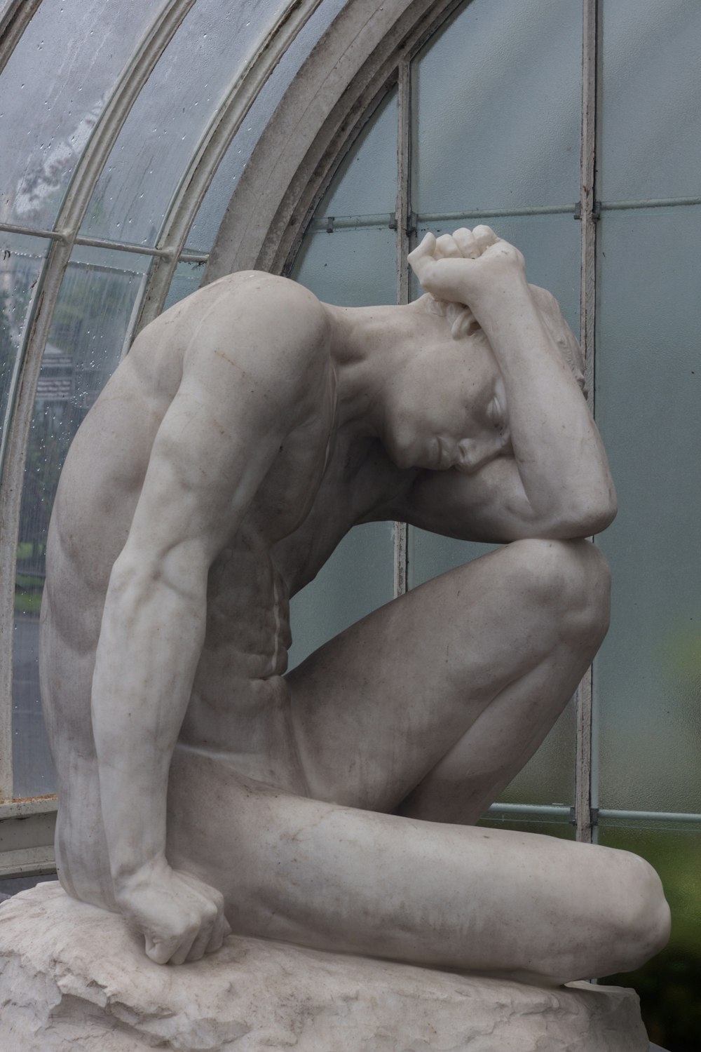 a statue of a man sitting in front of a window