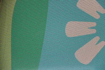 A close-up of a surface with a pattern of small, evenly spaced black dots overlaid on a background featuring shades of green and beige. On the right, there are stylized, abstract shapes resembling leaves or petals in a lighter beige color.