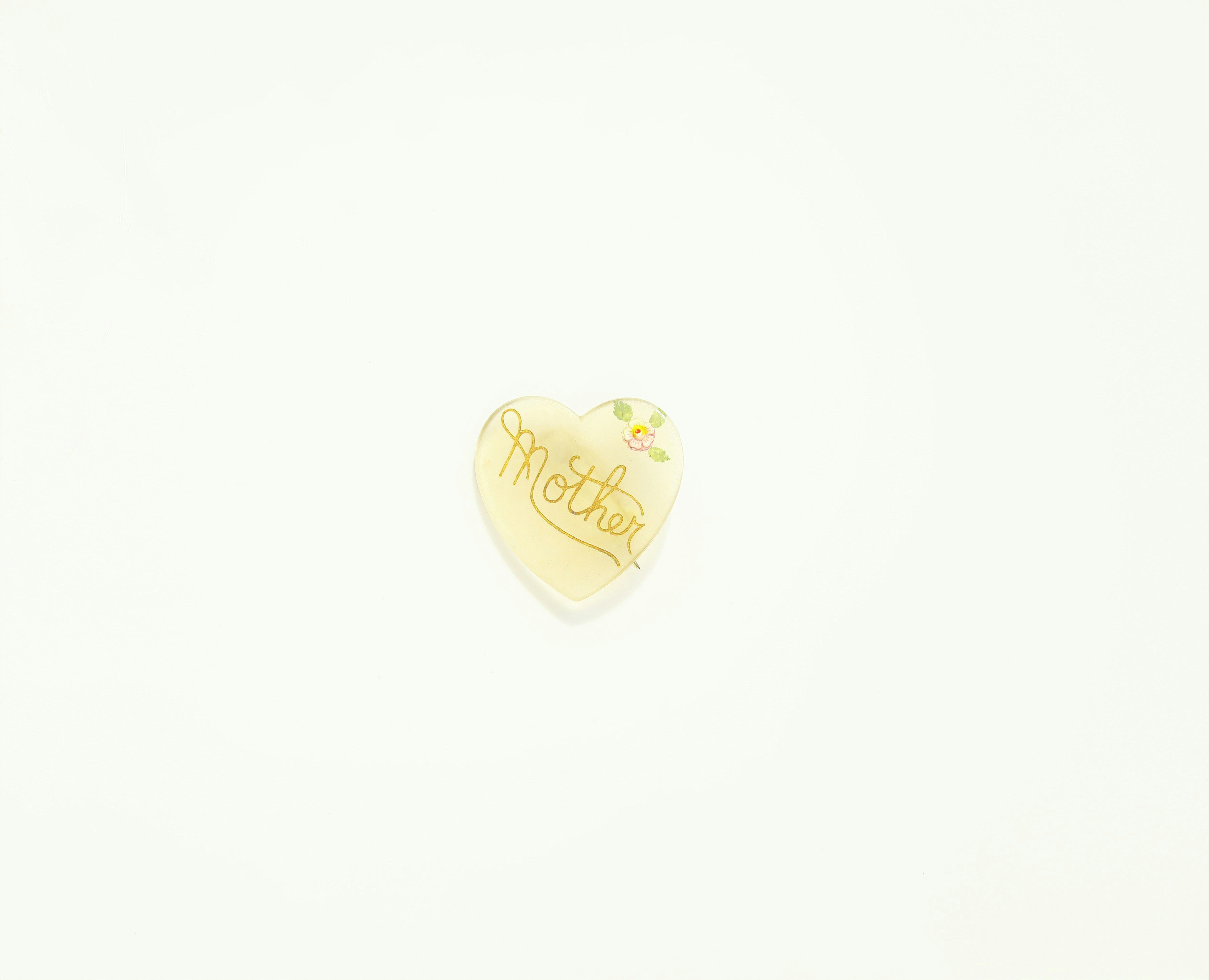 a heart shaped brooch with a name written on it