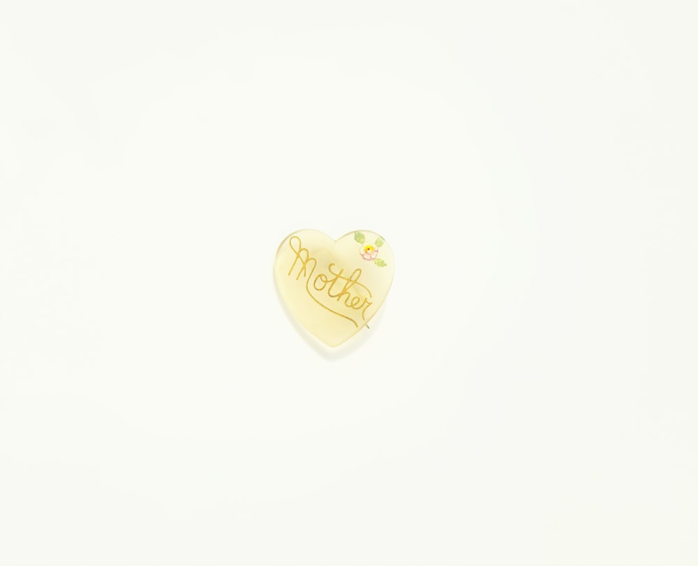 a heart shaped brooch with a name written on it