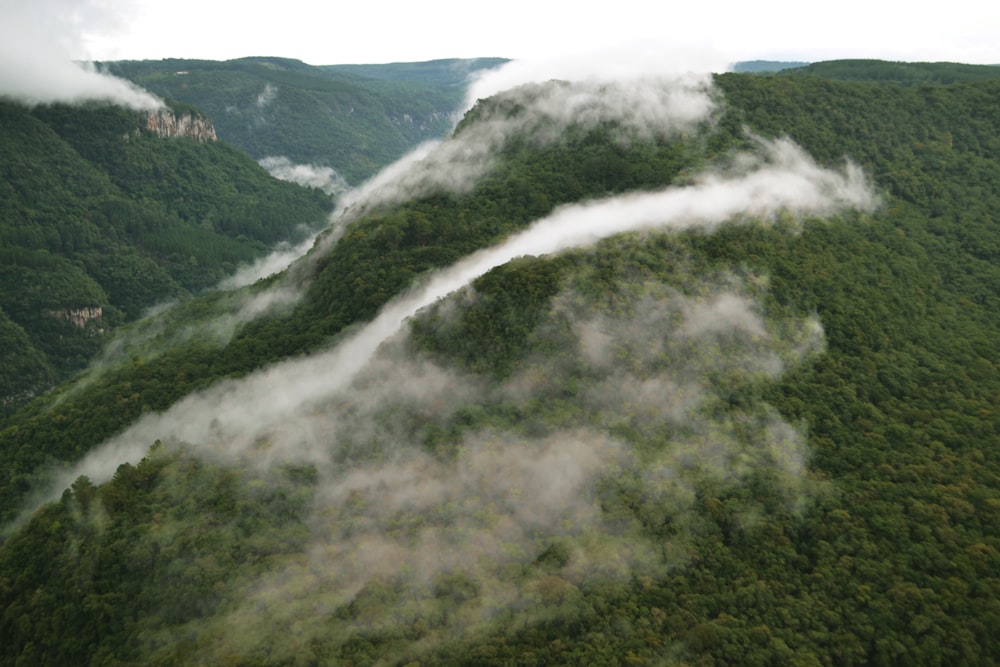 an aerial view of a green mountain with low lying clouds