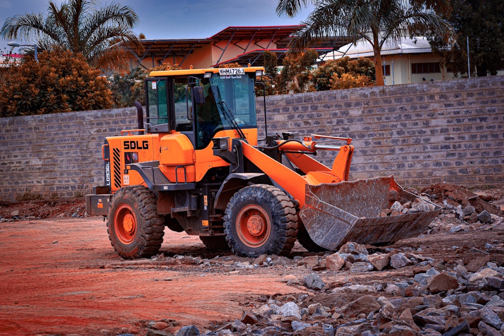 un grand bulldozer orange assis au sommet d’un champ de terre