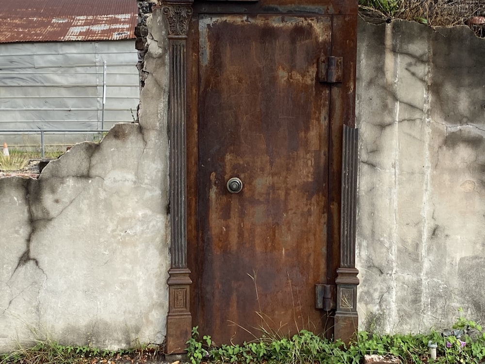 an old wooden door in front of a concrete wall