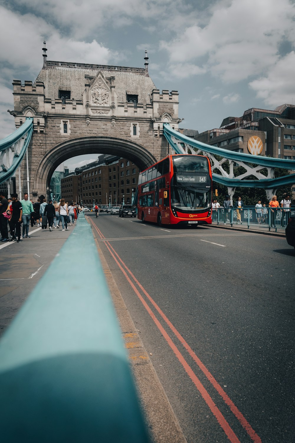 a red double decker bus driving under a bridge